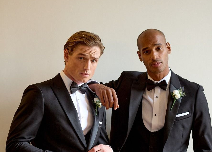 Two grooms in black tuxedos with bow ties and white pocket squares, photographed by Bell and Sons